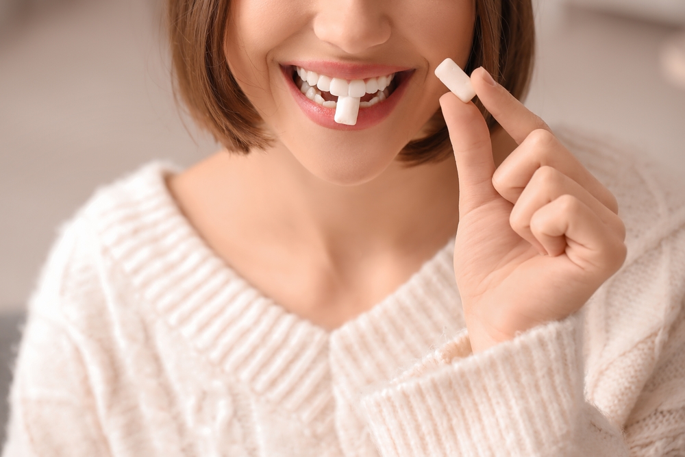 A woman holding a toothbrush in her mouth, indicating she is about to start brushing her teeth.
