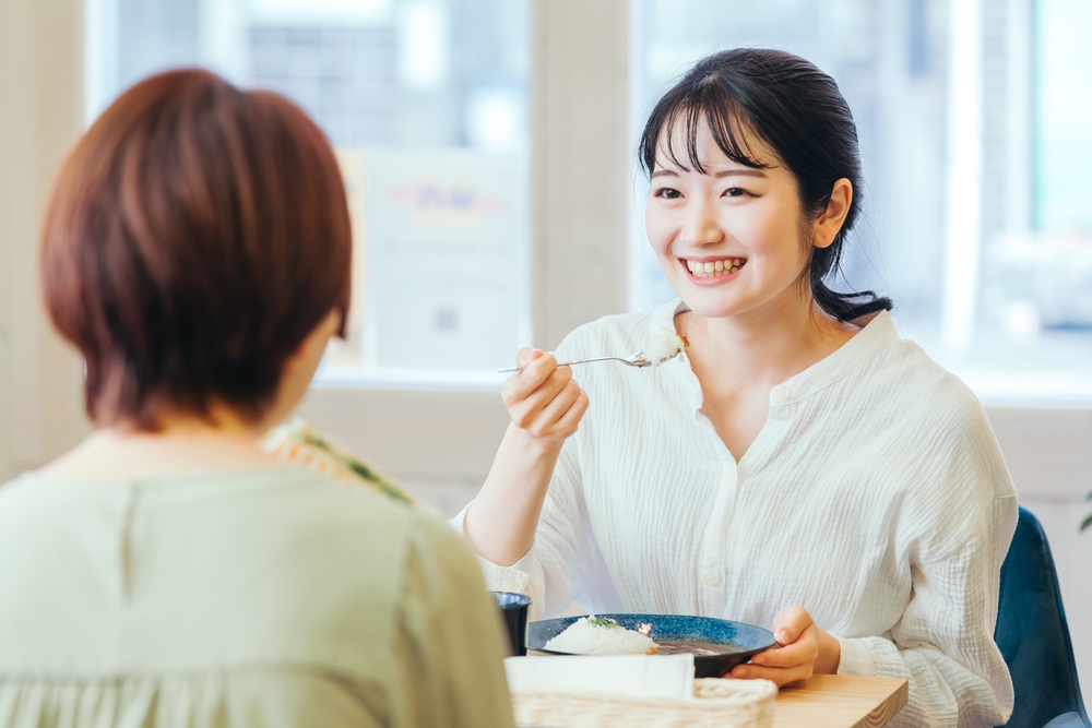 Two women share a meal together, enjoying each other's company at a dining table.